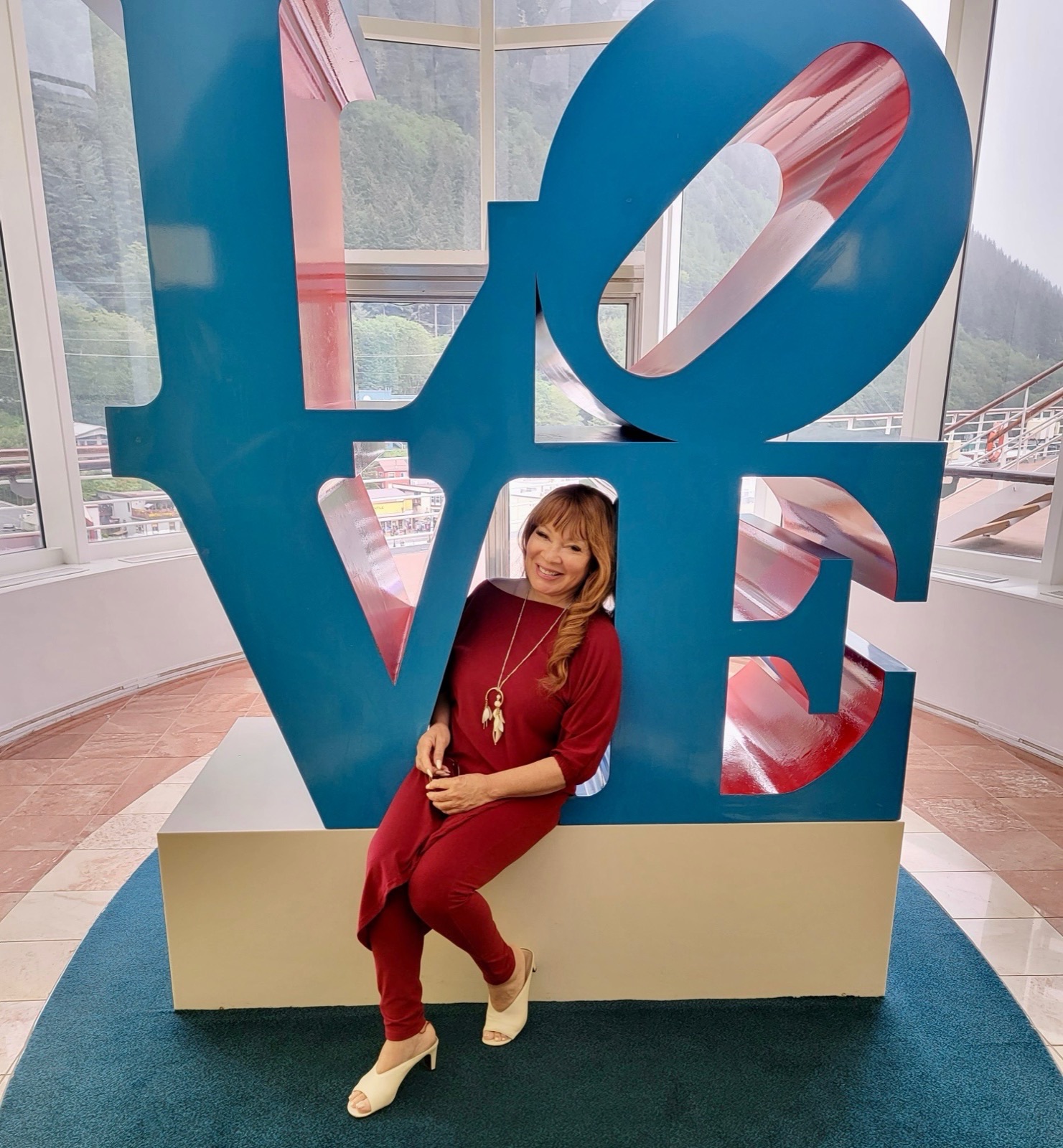 Dr. Deborah Egerton is sitting on a statue that spells out "LOVE"
